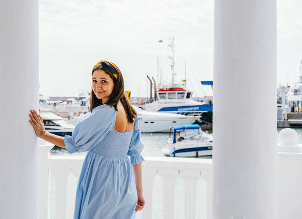 Portrait of young beautiful woman in blue dress on the shore against the background of yachts. Sea voyage concept. - Foto, afbeelding