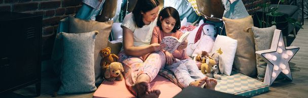 Mère et fille faisant une fête pyjama lisant un livre - Photo, image