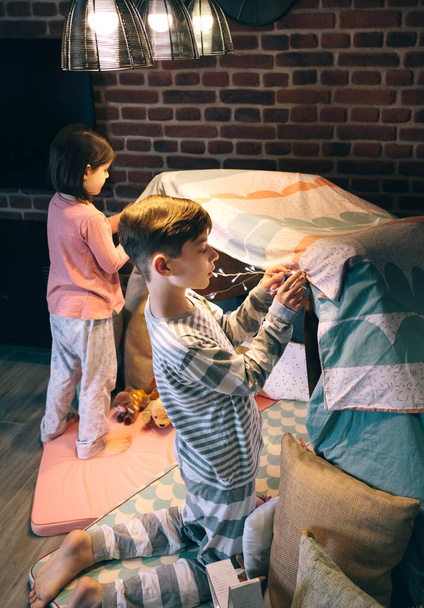 A fiú segít a nővérének fényfüzért rakni a sátorba. - Fotó, kép