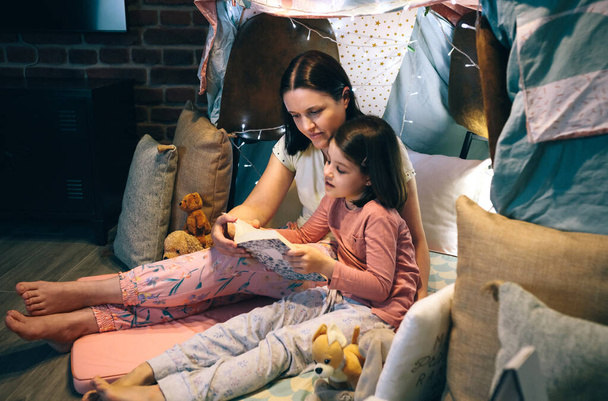 Mère et fille lisant un livre dans une tente de bricolage - Photo, image