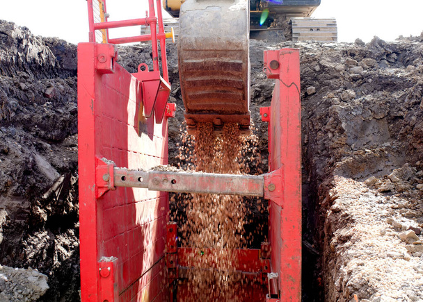 excavadora relleno inmersión excavación apoyada por caja de trinchera con tubo de lecho grava guisante durante la instalación de tubería de drenaje - Foto, Imagen