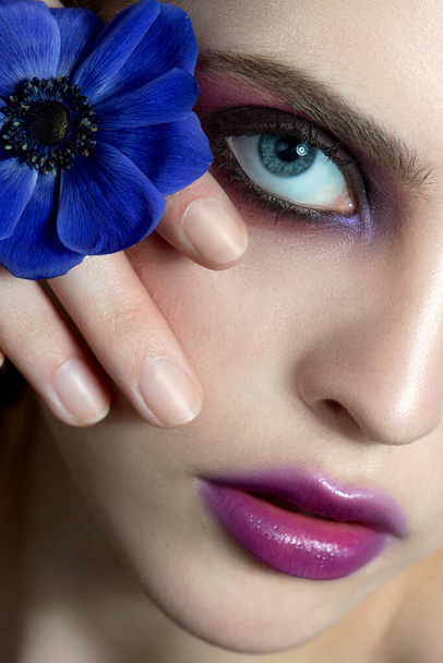 Beautiful young woman with perfect skin, creative make up and flower. Macro, Close up of fashion model face with nice professional make-up. SPA, wellness, bodycare and skincare concept. - 写真・画像