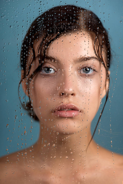 Beautiful young woman with clean perfect skin and water moisture drops touching face. Portrait of beauty model with natural nude makeup moisturizing her skin by lotion. Spa, skincare and wellness. Close up, background, copy space. - Φωτογραφία, εικόνα