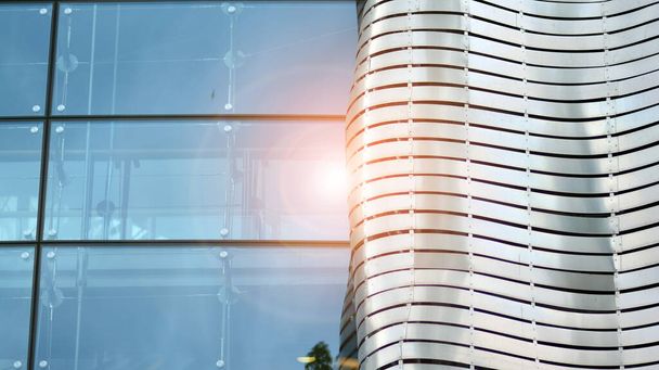 Fragment of the facade.  Facade texture of a glass mirrored office building. Light at sunrise with lens flare.  - Photo, Image