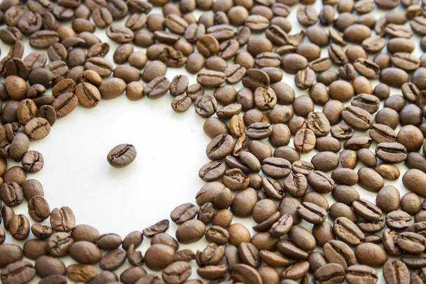 A closeup of the roasted coffee beans scattered on the white surface - Fotó, kép