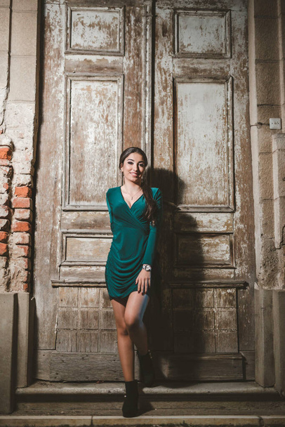 A vertical shot of a white Caucasian woman wearing a green evening dress and posing for a picture - Foto, Bild