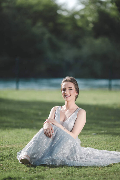 A young attractive Caucasian female with makeup wearing a beautiful evening gown and posing outdoors - Фото, зображення