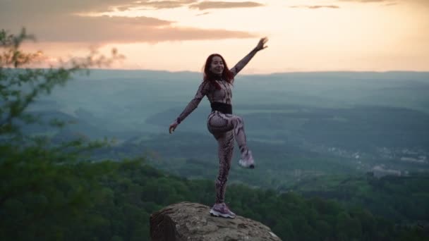 Αθλητική γυναίκα που απλώνεται ενάντια στο εκπληκτικό ορεινό τοπίο. Κορίτσι που κάνει σχισμές - Πλάνα, βίντεο