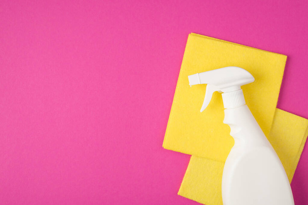 Top view photo of white spray detergent bottle without label and two yellow viscose rags on isolated pink background with copyspace - Photo, Image