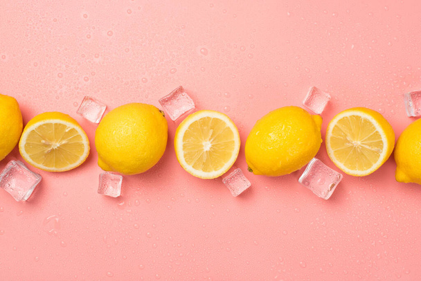 Photo de vue du dessus de la ligne horizontale de coupe et de citrons jaunes entiers glaçons gouttes d'eau sur fond rose pastel isolé - Photo, image