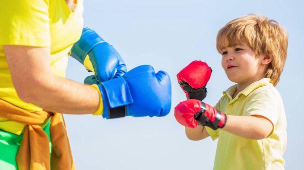 Otec trénuje svého syna v boxu. Malý sportovec na boxerském tréninku s trenérem. Malý chlapec dělá boxerské cvičení s dědečkem - Fotografie, Obrázek