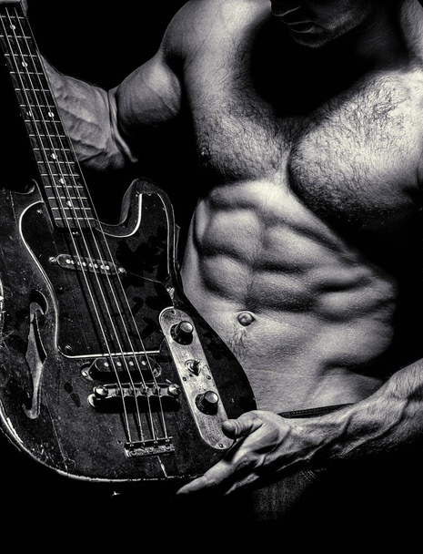 Electric guitar. Torso man. Instrument on stage and band. Strong, muscular, muscles man, bodybuilding. Music concept. Play the guitar. Chest muscles. Black and white - Foto, imagen