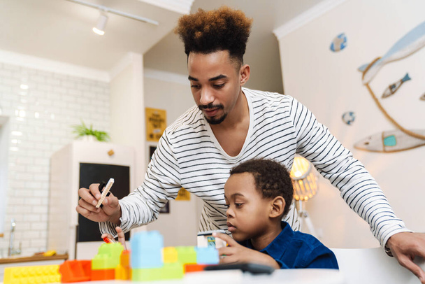 Focused african american boy playing with her young father at home - Photo, image