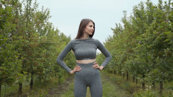 Portrait of happy beautiful positive fit girl, young slim fitness sports woman in sportswear, top outdoors going to training in park and smiling, looking at camera. New normal sport outdoor. - Photo, Image