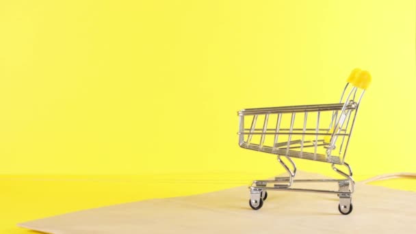 Leere Einkaufswagen auf gelbem Hintergrund, Nahaufnahme. Black Friday Shopping und Discount-Konzept - Filmmaterial, Video