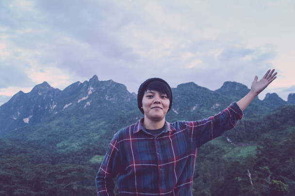 Hombre joven asiático en camisa escocesa y sombrero negro senderismo de pie brazo abierto feliz en el pico de la montaña por encima de las nubes y la niebla Hiker al aire libre. Doi Luang Chiang Dao Chiangmai Provincia, Por la mañana. - Foto, Imagen