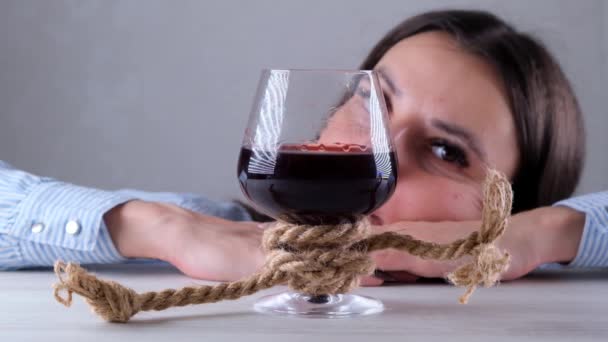 正義のロープで結ばれた悲しい女のワイングラス。アルコール依存症の概念。アルコール依存症の治療の問題 - 映像、動画