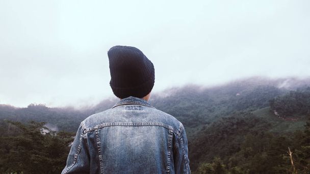Joven asiático en Jean jecket y sombrero negro senderismo en la cima de la montaña por encima de las nubes y la niebla Hiker al aire libre. Doi Luang Chiang Dao Chiangmai Provincia, Por la mañana. - Foto, Imagen