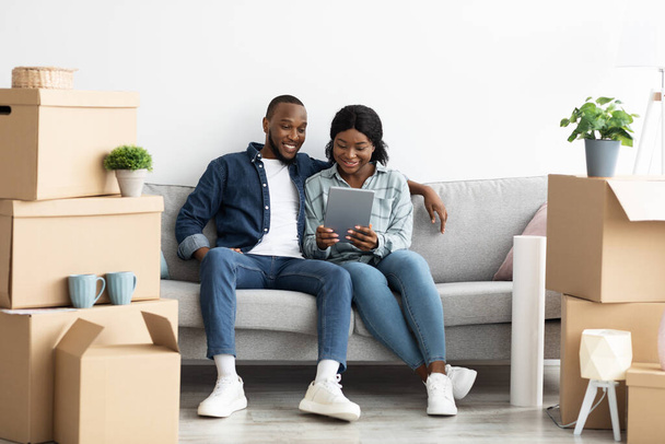 Onnellinen musta pari käyttäen digitaalinen tabletti yhdessä muutettuaan uuteen kotiin - Valokuva, kuva