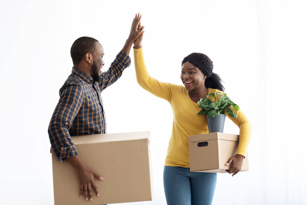 Boldog fiatal fekete pár, akik pacsiznak, ünneplik, hogy új házba költöznek. - Fotó, kép