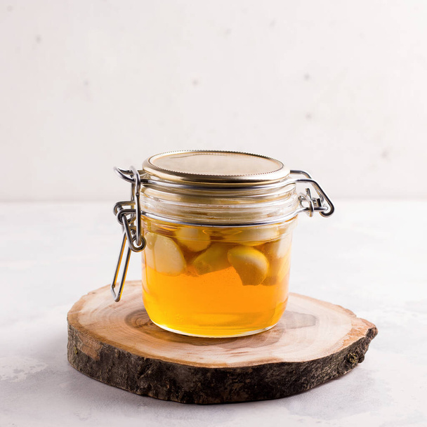 Fermentierte Lebensmittel. Honig mit Knoblauch auf weißem Hintergrund - Foto, Bild