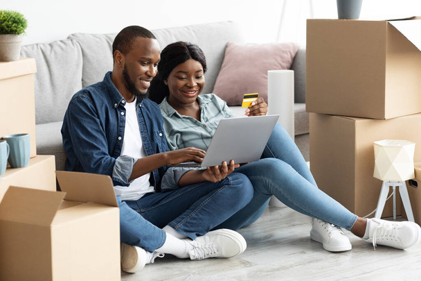 Black Married Couple Shopping Online With Laptop And Credit Card After Moving - Valokuva, kuva