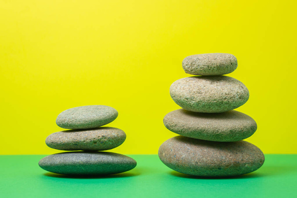 Flat stones stacked on top of each other on a colored background. The concept of calmness and balance - Photo, Image