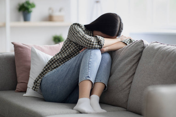 Sconvolto giovane donna seduta sul divano e piangendo - Foto, immagini