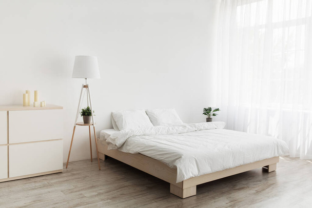 Einfaches modernes Design, Anzeige, Angebot. Doppelbett mit weißen Kissen und weicher Decke, Lampe, Möbel auf Holzboden - Foto, Bild