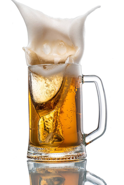splash from falling ice into glass with foamy beer on white background isolated - Fotografie, Obrázek