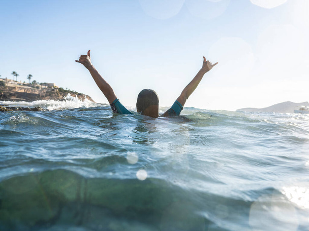 woman in the water raising hands in the sea, vacation concept - 写真・画像