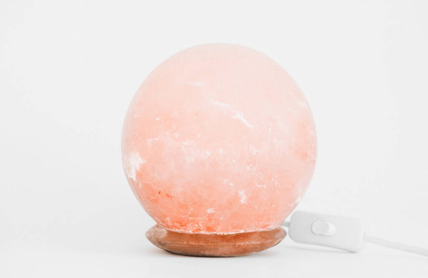 round himalayan Pink salt lamp on white background. wellness and clean air in the room. healthy sleep help - Photo, Image