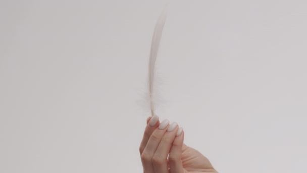 Concepto de piel lisa y cuidado corporal. Primer plano de la mujer sosteniendo pluma blanca en su mano - Imágenes, Vídeo