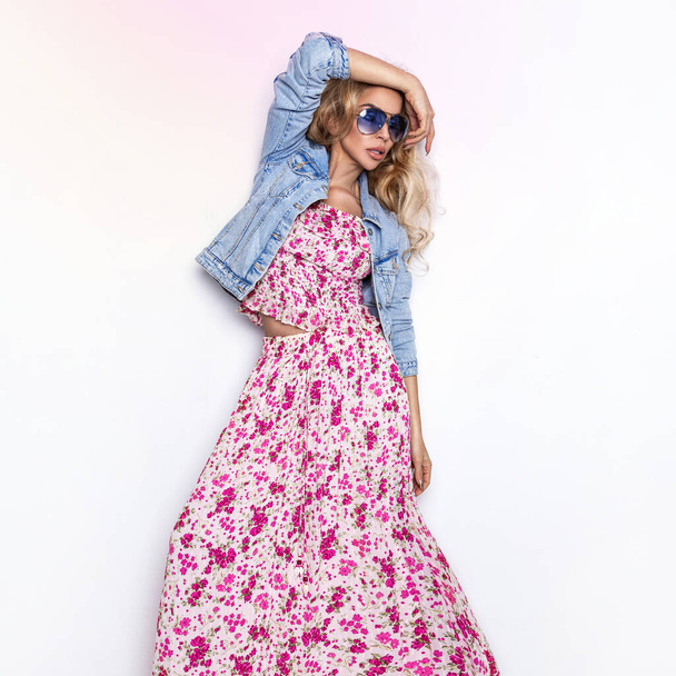 Fashion photo of a beautiful elegant young woman in a pretty dress with flowers and jeans jacket posing over white background. Fashion photo. Spring fashion. - Photo, Image