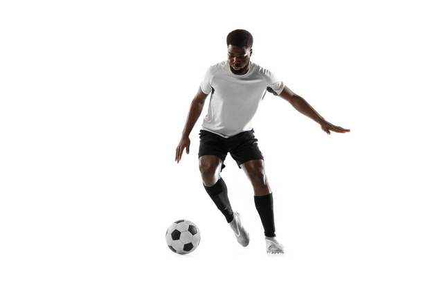 Un footballeur africain s'entraîne isolé sur fond blanc. Concept de sport, mouvement, énergie et dynamisme. - Photo, image