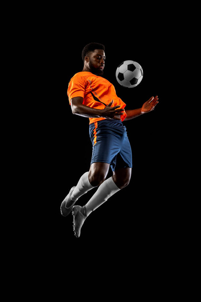 One African football soccer player playing isolated on black background. Concept of sport. - Φωτογραφία, εικόνα