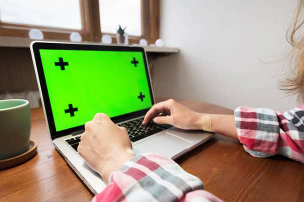 Woman using laptop with green screen. Business, communication, freelance and internet concept. Working at a laptop at home - Foto, Bild