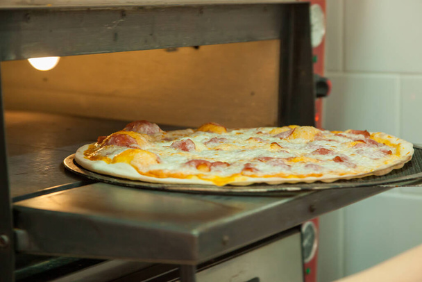 Delgada deliciosa pizza se cuece en el horno. - Foto, Imagen