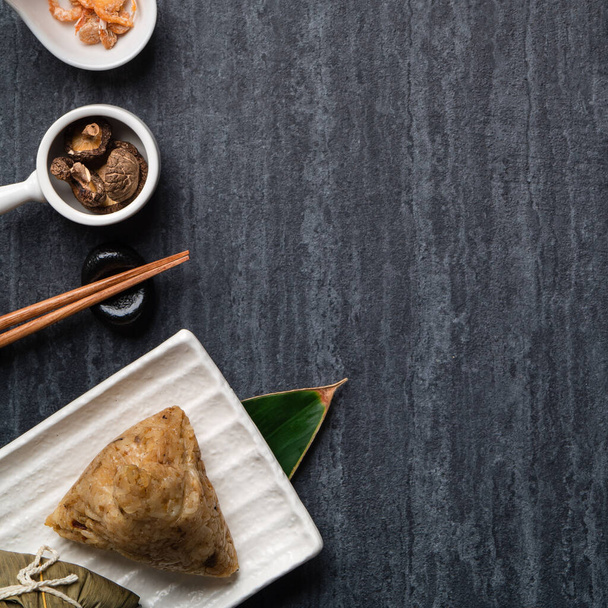 Zongzi. Rice dumpling top view design concept for Chinese traditional Dragon Boat Festival (Duanwu Festival) over dark black slate background. - Foto, Bild