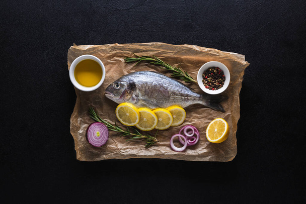 Dorado fish on a cutting board and on parchment paper with lemon and spices. - 写真・画像