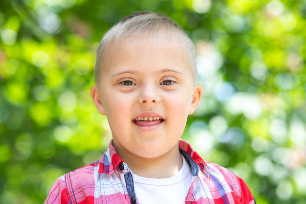 Πορτρέτο ενός αγοριού με σύνδρομο Down, ανάπηρο παιδί, ένα παιδί με γενετική χρωμοσωμική νόσο. - Φωτογραφία, εικόνα