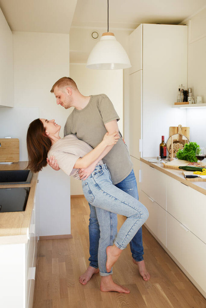 love, dating and relationship concept - young couple cooking and dancing in the kitchen - Foto, imagen