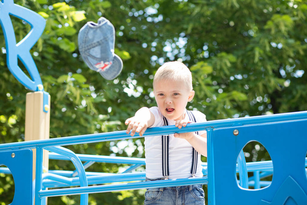 Un niño con síndrome de Down juega en el patio de recreo, un niño con discapacidad, un niño con un cromosoma adicional. - Foto, imagen