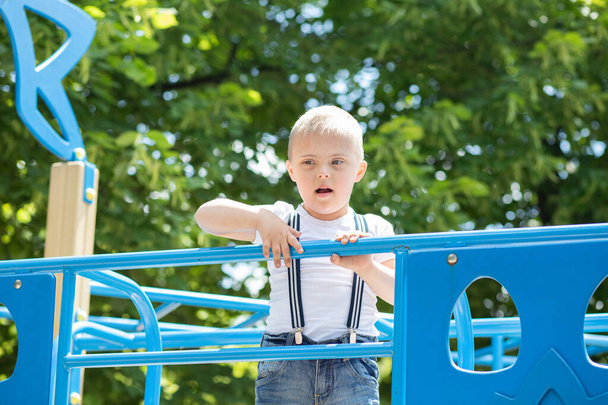 Chlapec s Downovým syndromem hraje na hřišti, postižené dítě, dítě s extra chromozomem. - Fotografie, Obrázek