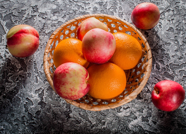 Fresh fruits. Nectarines and oranges on the table. - Photo, Image