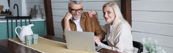 Mosolygó idős pár használ laptop konyhaasztalon, banner  - Fotó, kép