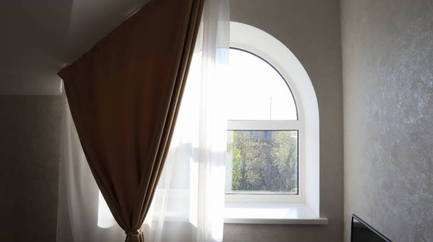 Gewölbefenster im Wohnzimmer mit Tüll und Vorhang. Moderne und helle Schlafzimmereinrichtung - Foto, Bild