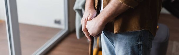 Cropped view of senior man with crutch standing at home, banner  - Foto, imagen