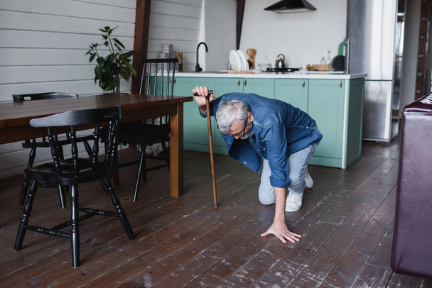 Homem idoso com muleta caindo no chão em casa  - Foto, Imagem