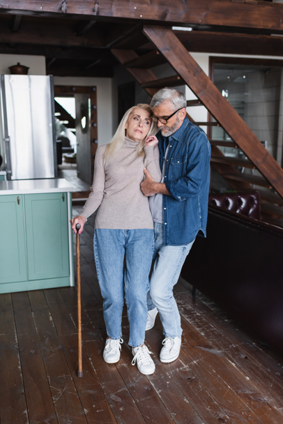 Älterer Mann hilft Ehefrau mit Krücke zu Hause  - Foto, Bild